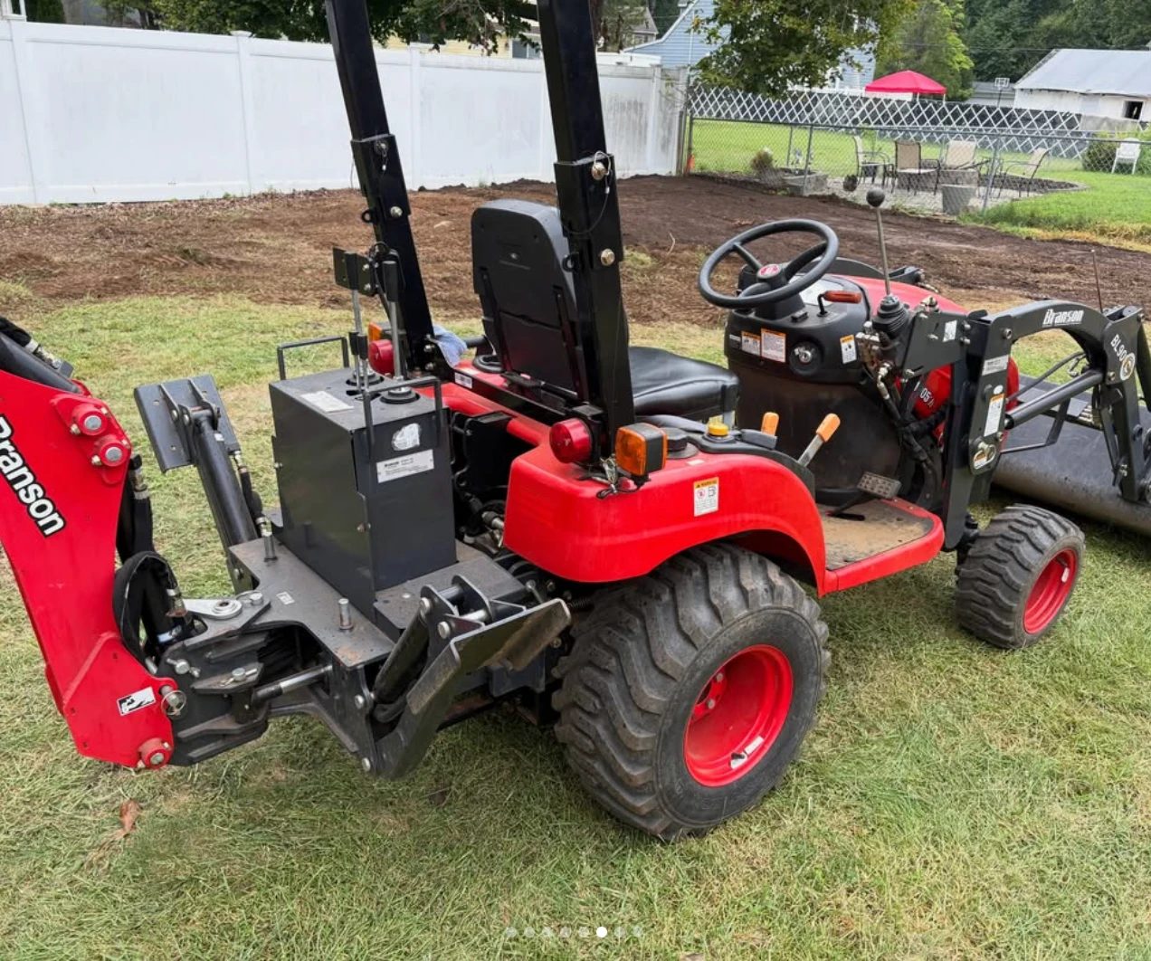 Compact tractor with loader and backhoe used for land clearing and grading